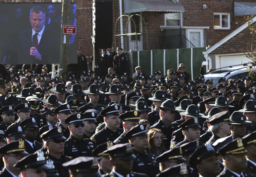 Law enforcement officers turn their backs on a video monitor as New York City Mayor de Blasio speaks during the funeral of slain NYPD officer Rafael Ramos near Christ Tabernacle Church in the Queens borough of New York
